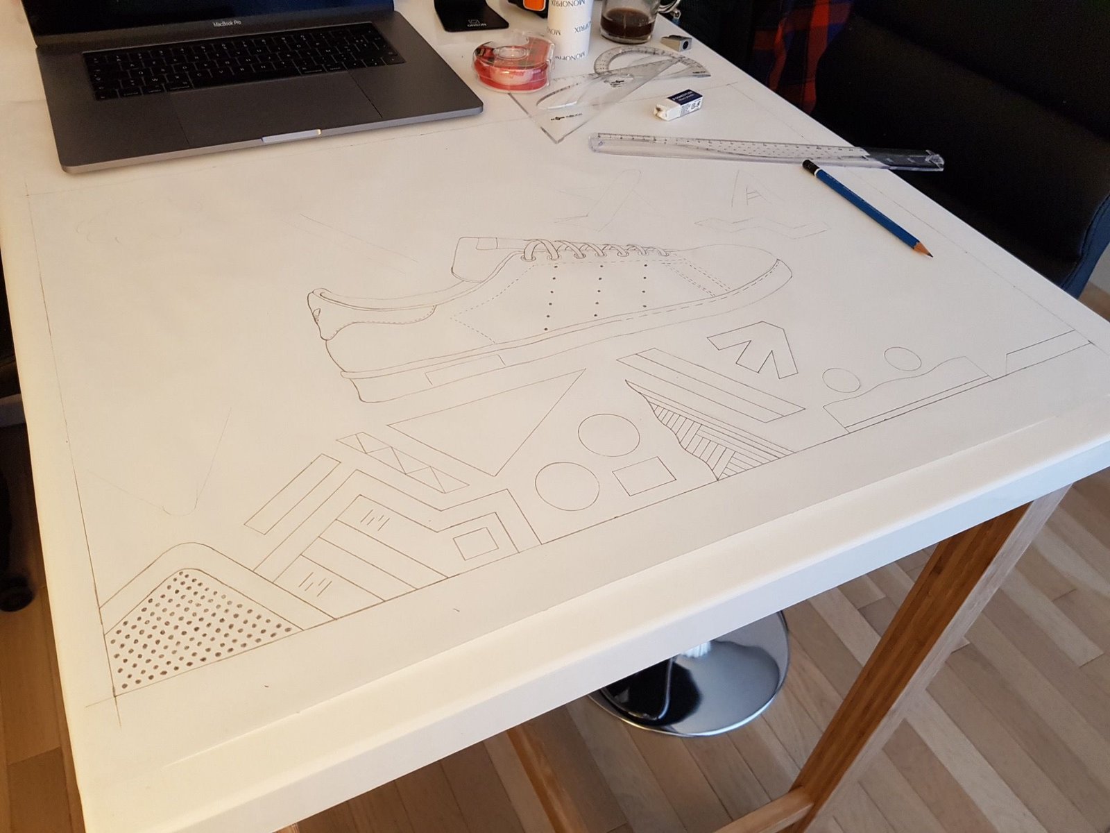 Le croquis de la Stan Smith dessiné au crayon sur une grande feuille, posée sur le bureau.